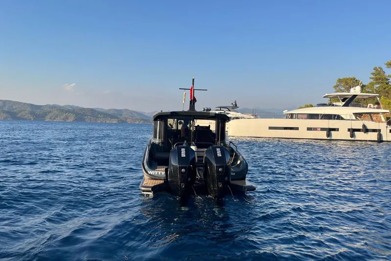  Yacht Photos Pics 2021 XO EXPLORER 10S boat on serene blue water, with distant hills and another yacht.