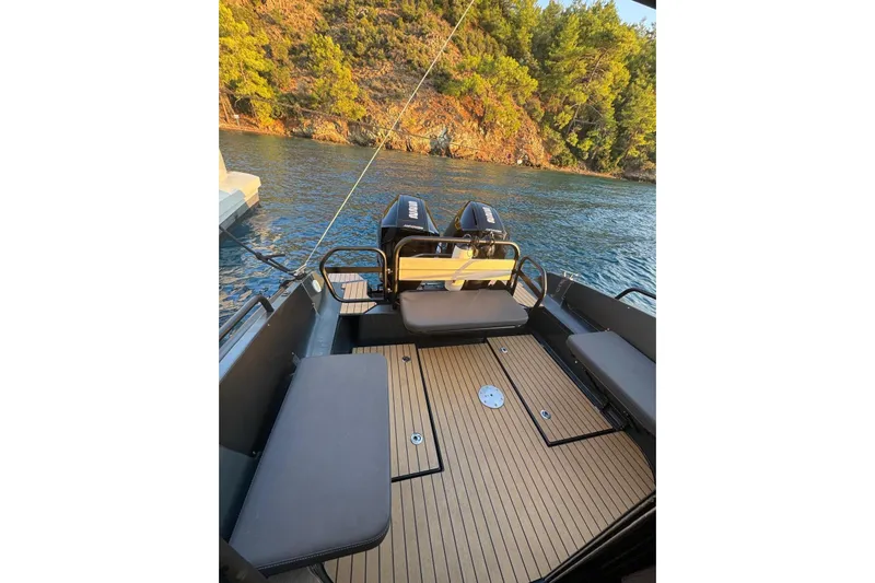  Yacht Photos Pics 2021 XO EXPLORER 10S boat interior with seating, docked by a scenic shoreline.