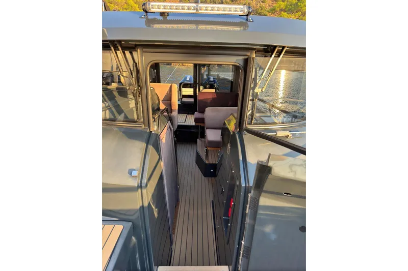  Yacht Photos Pics 2021 XO EXPLORER 10S boat interior with seating, docked on calm water.