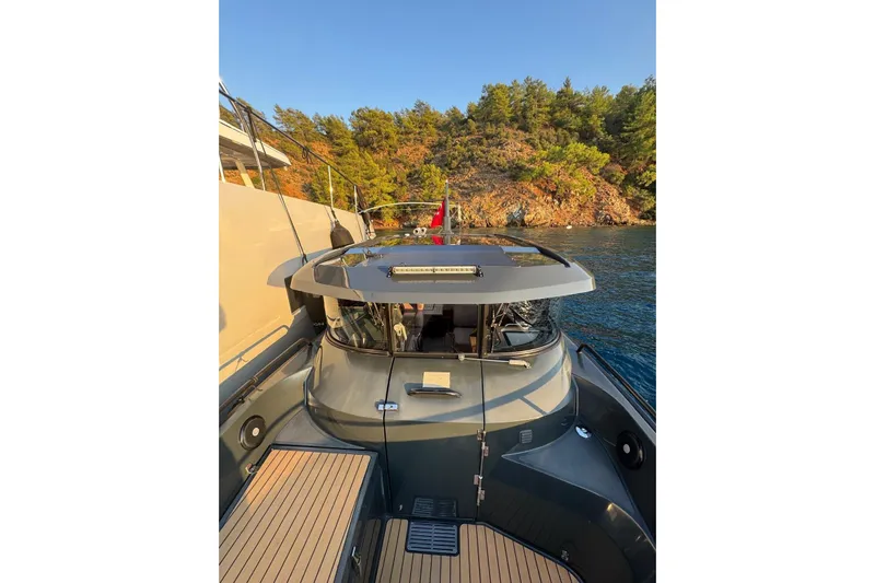  Yacht Photos Pics 2021 XO EXPLORER 10S boat docked near scenic rocky shoreline.