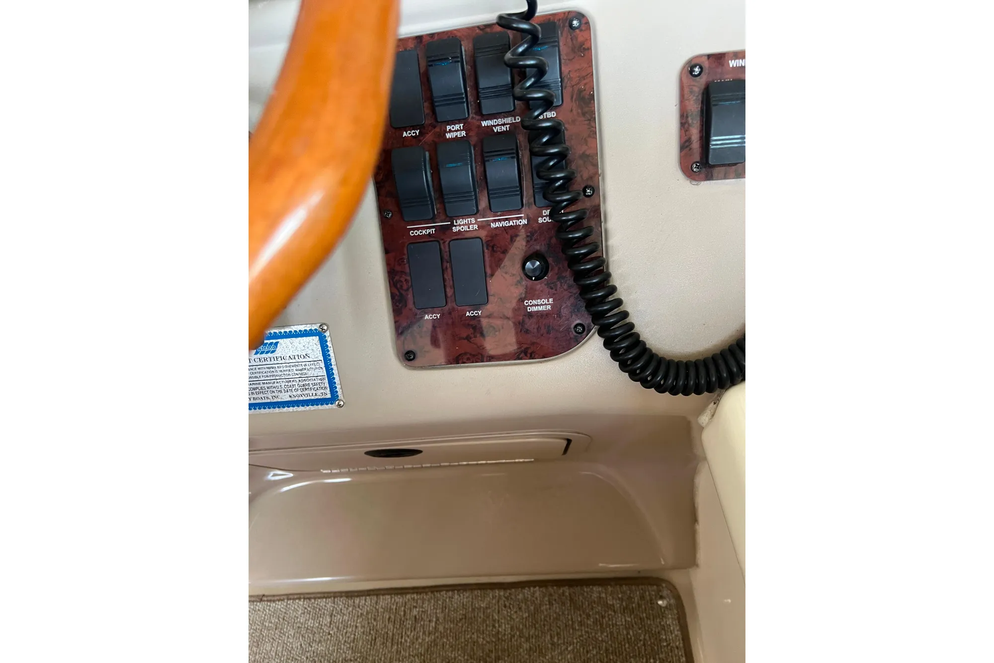 Control panel of a 1999 Sea Ray 290 Sundancer boat with switches and coiled cord.