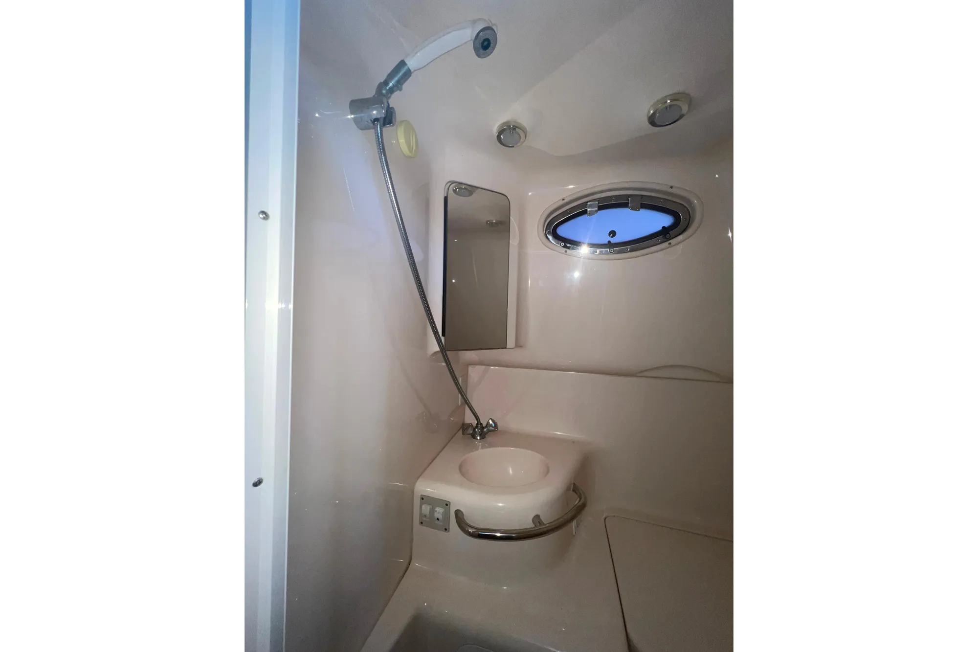 1999 Sea Ray 290 Sundancer bathroom with shower, sink, and porthole window.