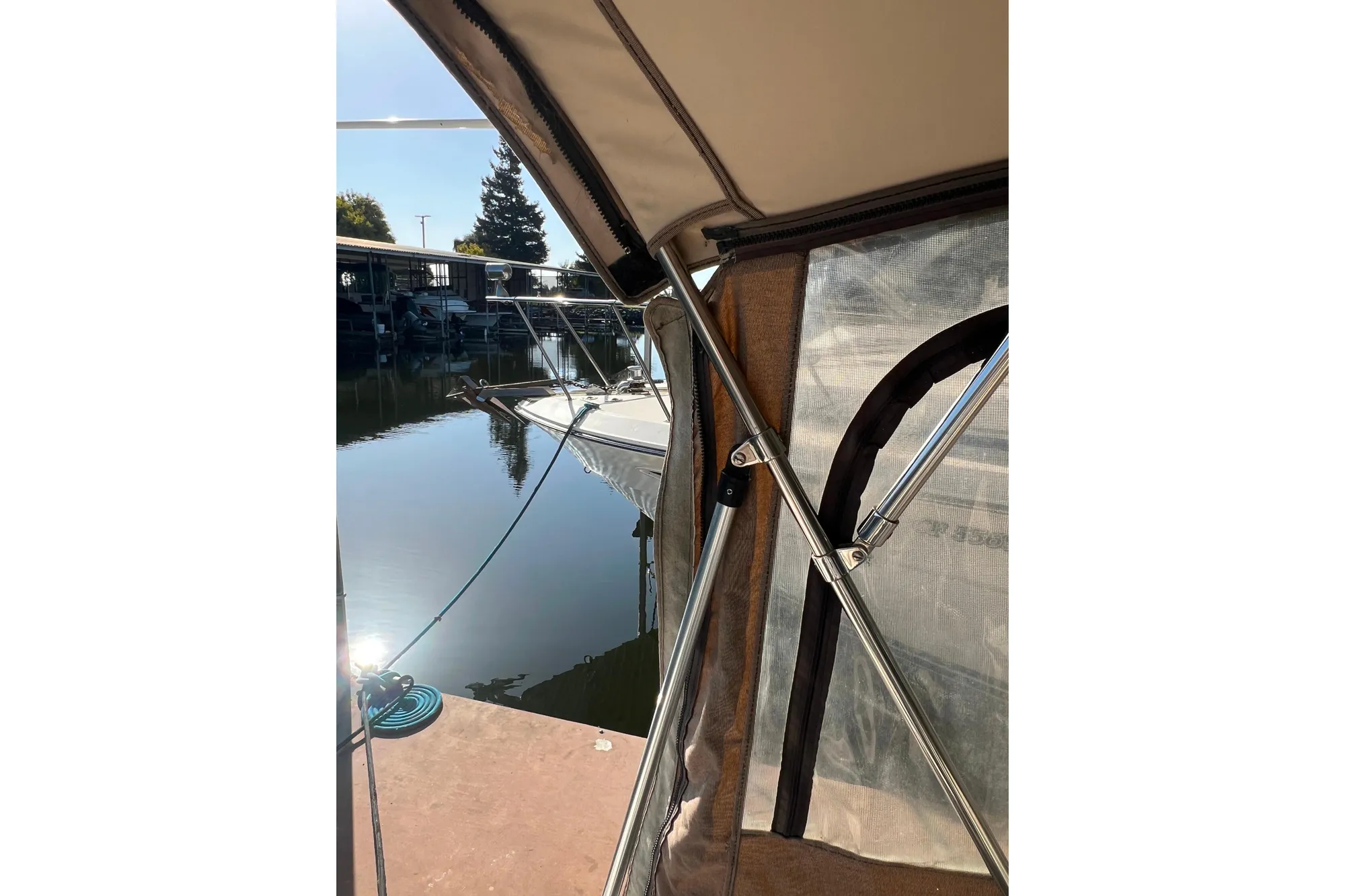 1999 Sea Ray 290 Sundancer docked, viewed from under a boat canopy.
