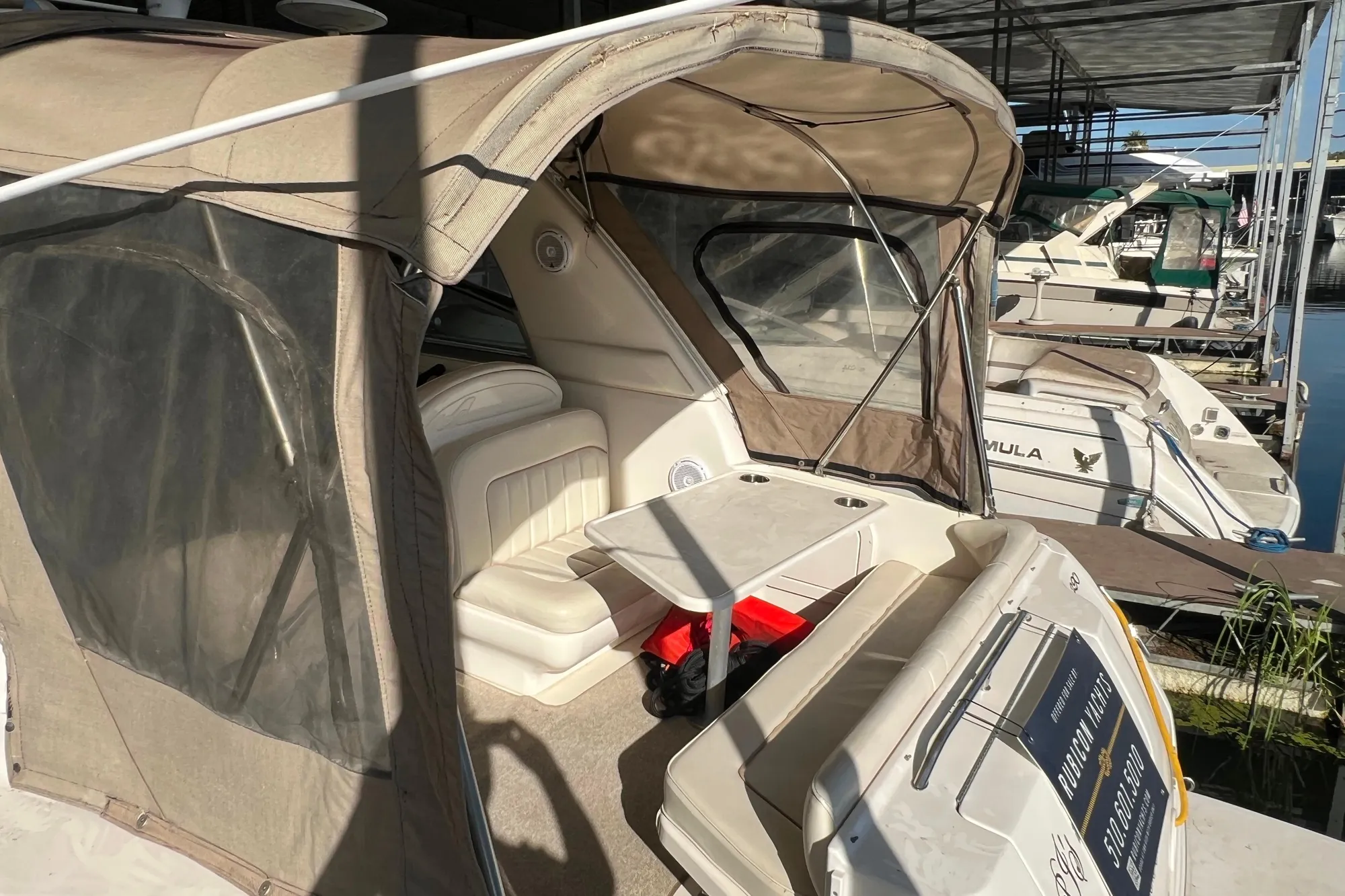 1999 Sea Ray 290 Sundancer boat with beige canopy docked at marina.