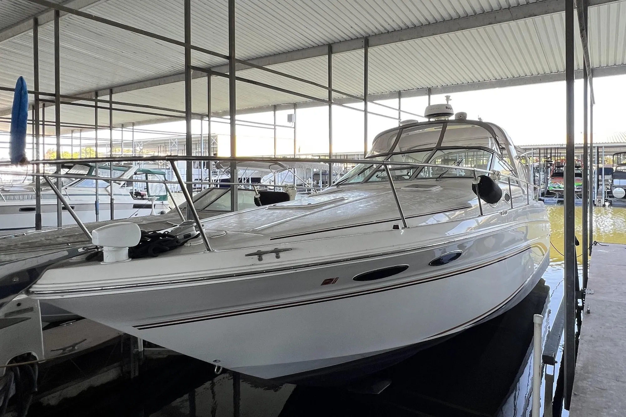 1999 Sea Ray 290 Sundancer docked in a covered marina, showcasing sleek design.