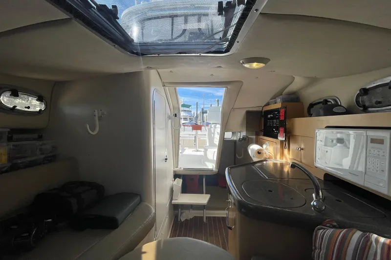 Mad Fish Yacht Photos Pics Interior of a 2001 Boston Whaler 28 Conquest boat, featuring a compact kitchen and seating area.