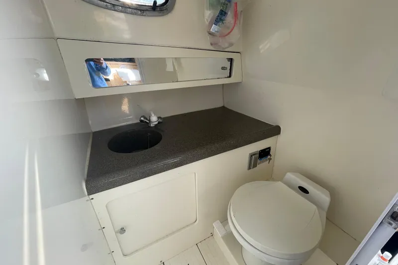 Mad Fish Yacht Photos Pics 2001 Boston Whaler 28 Conquest boat bathroom with sink, mirror, and toilet.
