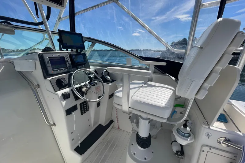 Mad Fish Yacht Photos Pics 2001 Boston Whaler 28 Conquest helm with steering wheel, navigation screens, and captain's chair.