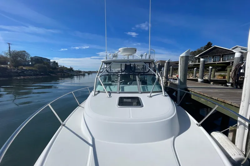 Mad Fish Yacht Photos Pics 2001 Boston Whaler 28 Conquest docked by a serene waterfront under a clear blue sky.
