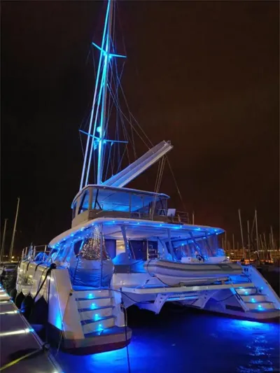 Tbd Yacht Photos Pics Luxurious 2022 Fountaine Pajot Samana 59 catamaran illuminated with blue lights at night.