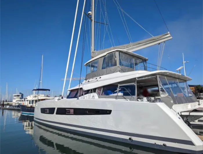 Tbd Yacht Photos Pics 2022 Fountaine Pajot Samana 59 catamaran docked in a marina under clear blue skies.
