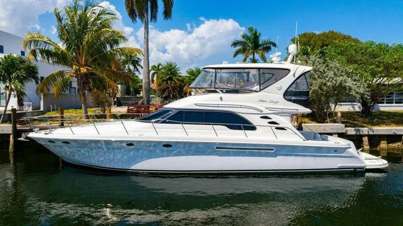 Southern Seas Yacht Photos Pics 1999 Sea Ray 56 Sedan Bridge yacht docked by palm trees, under a clear blue sky.