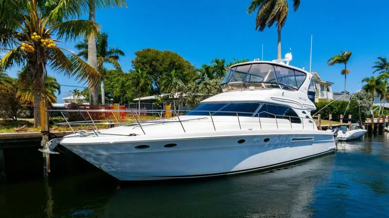 Southern Seas Yacht Photos Pics 1999 Sea Ray 56 Sedan Bridge yacht docked by palm trees, under clear blue sky.