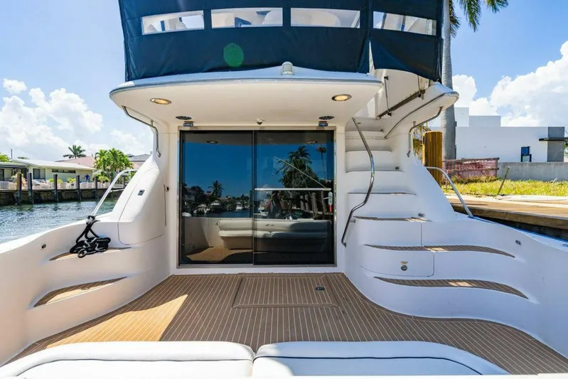 Southern Seas Yacht Photos Pics 1999 Sea Ray 56 Sedan Bridge yacht with elegant deck and staircase, docked by waterfront homes.