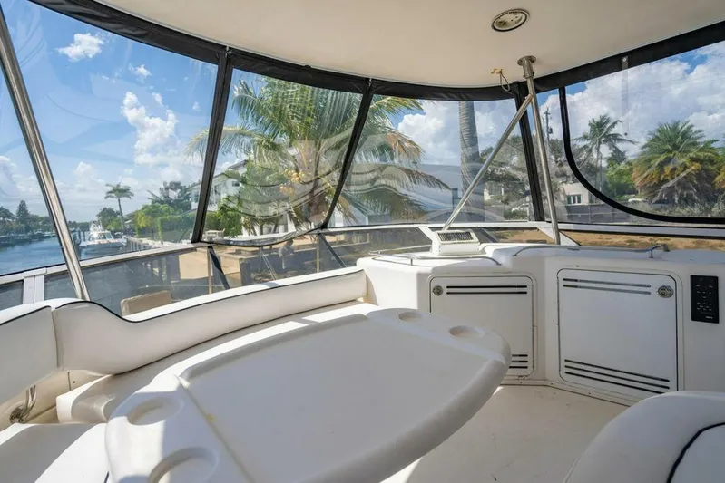 Southern Seas Yacht Photos Pics 1999 Sea Ray 56 Sedan Bridge interior with panoramic windows and seating, overlooking a tropical waterfront.