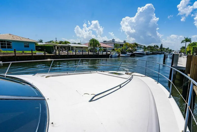 Southern Seas Yacht Photos Pics 1999 Sea Ray 56 Sedan Bridge yacht on a sunny waterfront, surrounded by houses and palm trees.