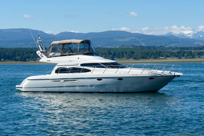 Italian Job Yacht Photos Pics 2001 Cranchi Atlantique yacht on serene water with mountainous backdrop.