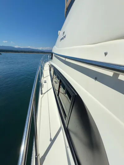 Italian Job Yacht Photos Pics 2001 Cranchi Atlantique yacht side view on calm water under clear blue sky.