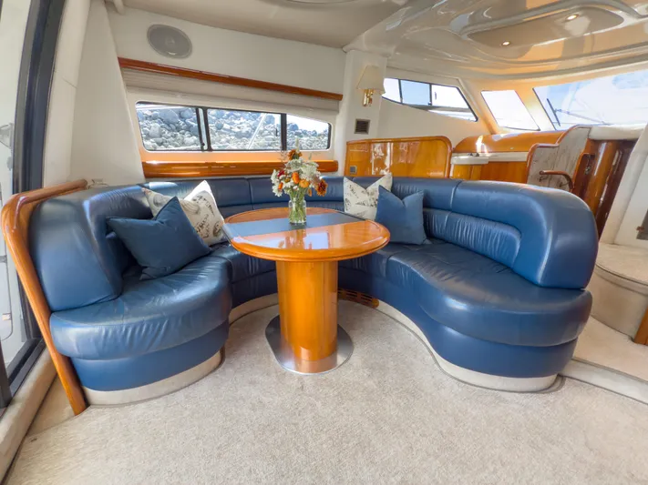 Italian Job Yacht Photos Pics Luxurious 2001 Cranchi Atlantique yacht interior with blue leather seating and wooden table.