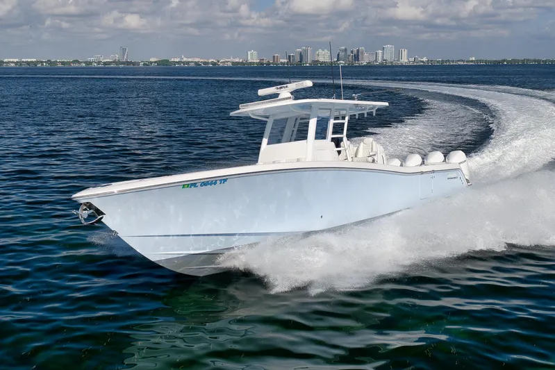  Yacht Photos Pics 2022 Invincible 39 Open Fisherman boat cruising on open water with city skyline backdrop.