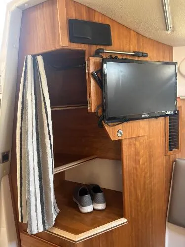  Yacht Photos Pics 2024 Cutwater C-32 C interior with TV, wooden shelves, and striped curtain.
