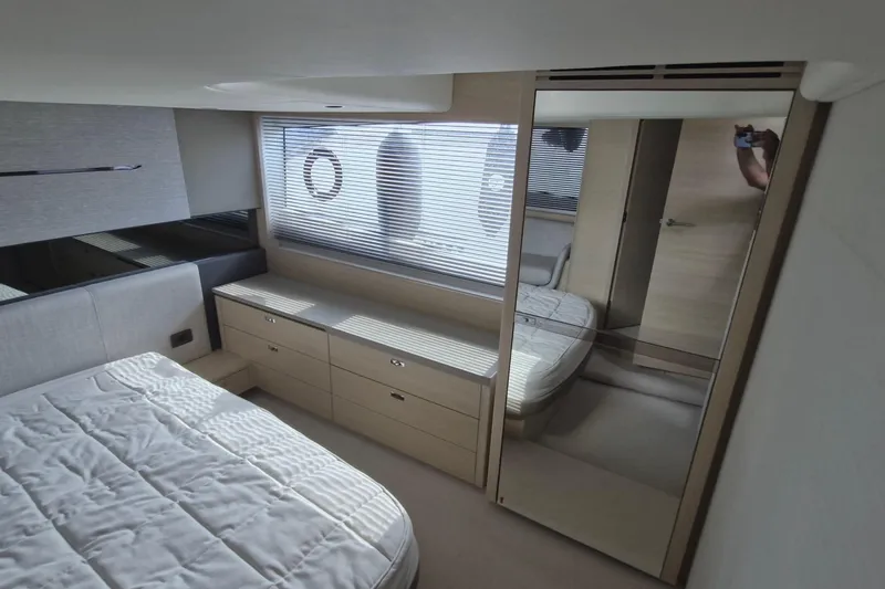  Yacht Photos Pics 2024 Princess V50 yacht interior cabin with bed, drawers, and mirrored closet.