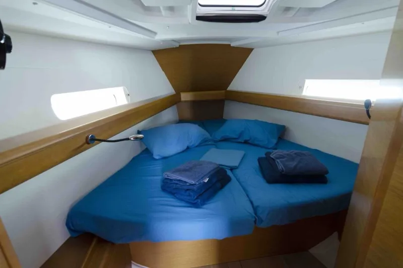  Yacht Photos Pics Cozy cabin interior of 2015 Jeanneau Sun Odyssey 409 sailboat with blue bedding.