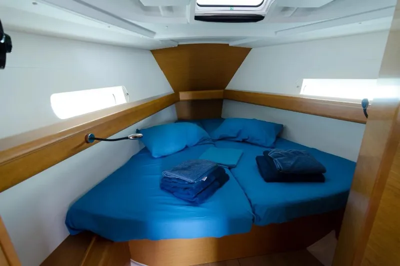  Yacht Photos Pics Cozy cabin interior of 2015 Jeanneau Sun Odyssey 409 sailboat with blue bedding.