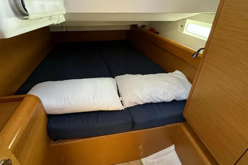  Yacht Photos Pics Cozy cabin interior of 2015 Jeanneau Sun Odyssey 409 sailboat with pillows and wooden finish.