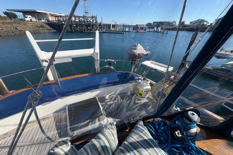 Tenacious Yacht Photos Pics 1987 Mikelson 50 yacht cockpit view with marina backdrop, featuring ropes and cushions.