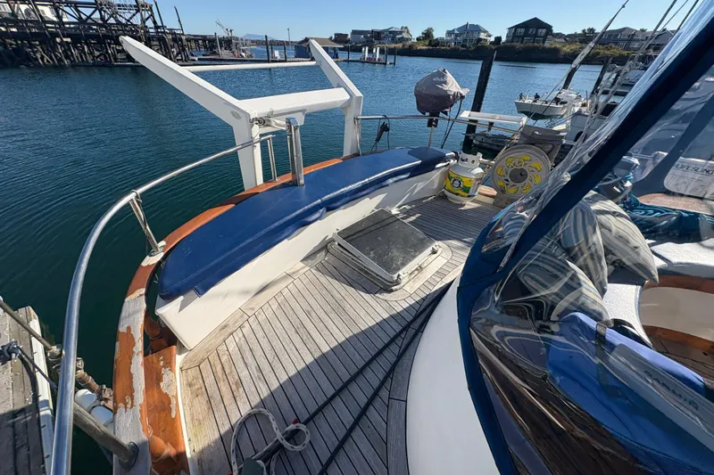 Tenacious Yacht Photos Pics 1987 Mikelson 50 yacht deck with blue seating, docked in a marina.