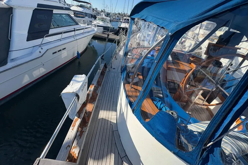 Tenacious Yacht Photos Pics 1987 Mikelson 50 yacht docked, featuring blue canopy and wooden deck details.