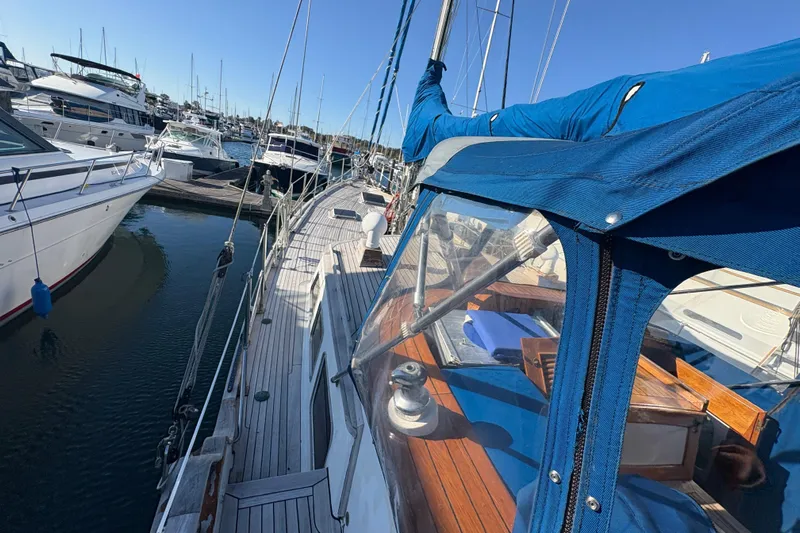 Tenacious Yacht Photos Pics 1987 Mikelson 50 yacht docked at marina, featuring blue canopy and wooden deck.