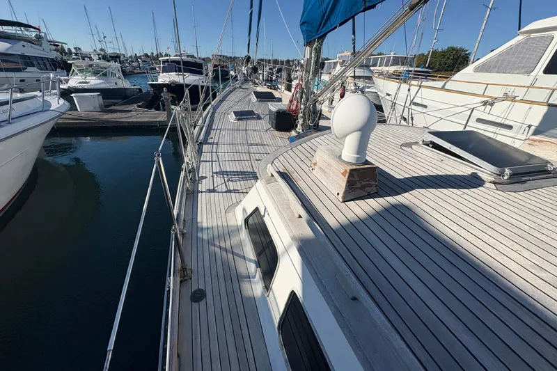 Tenacious Yacht Photos Pics 1987 Mikelson 50 yacht docked at marina, showcasing spacious wooden deck and clear blue sky.