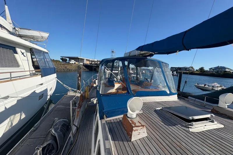 Tenacious Yacht Photos Pics 1987 Mikelson 50 yacht docked at marina, featuring blue canopy and wooden deck.