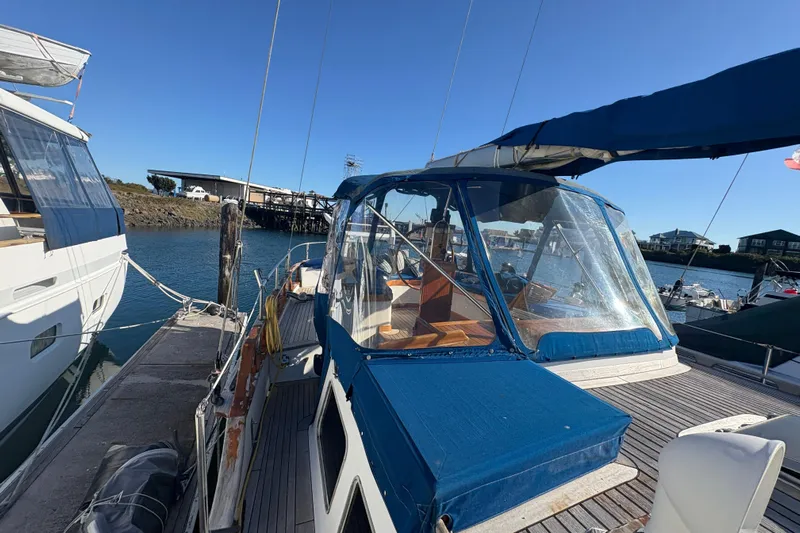 Tenacious Yacht Photos Pics 1987 Mikelson 50 yacht docked at marina, featuring blue canopy and wooden deck.