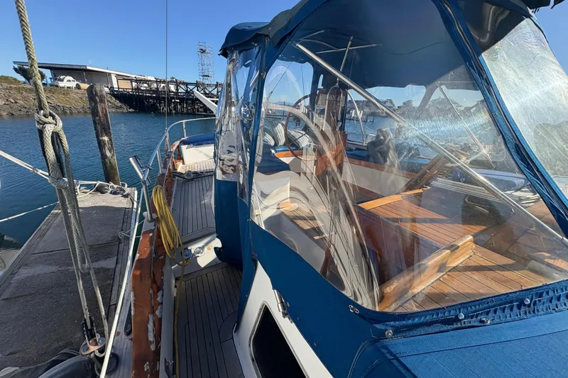 Tenacious Yacht Photos Pics 1987 Mikelson 50 yacht docked, featuring blue canopy and wooden deck.