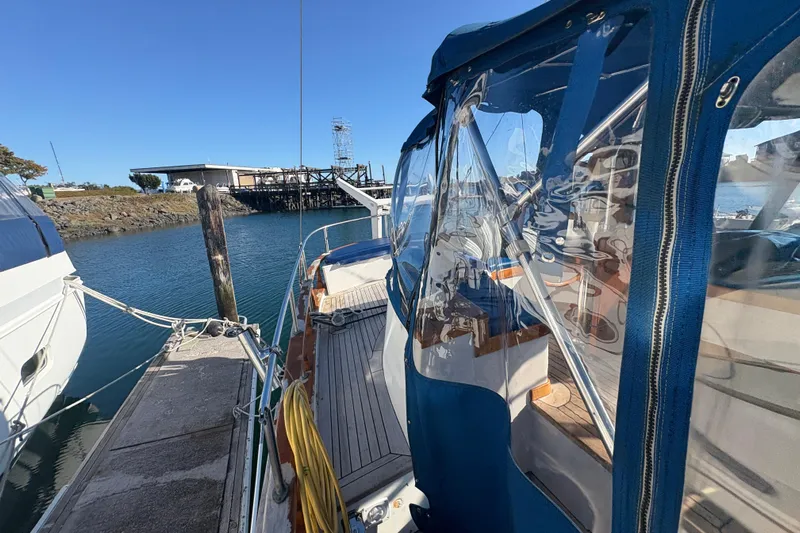 Tenacious Yacht Photos Pics 1987 Mikelson 50 yacht docked at marina, featuring blue canopy and clear windows.