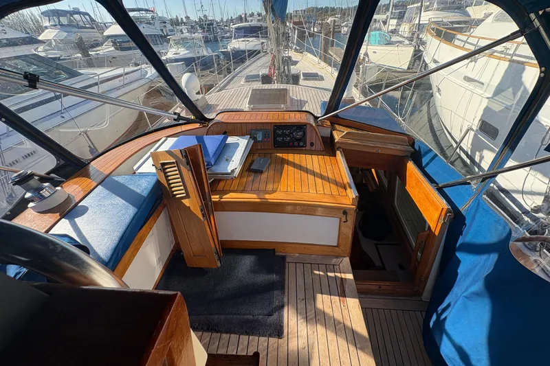 Tenacious Yacht Photos Pics Cockpit view of a 1987 Mikelson 50 yacht, featuring wooden accents and marina backdrop.