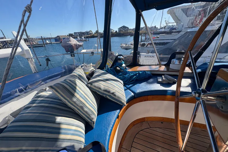 Tenacious Yacht Photos Pics Cozy cockpit of a 1987 Mikelson 50 yacht with striped cushions and marina view.