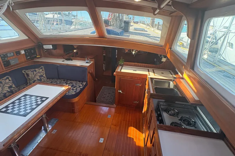 Tenacious Yacht Photos Pics Interior of a 1987 Mikelson 50 yacht with wood finish, seating, and kitchen area.