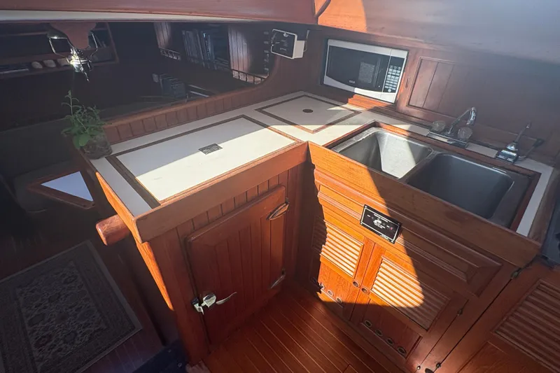 Tenacious Yacht Photos Pics Interior of 1987 Mikelson 50 yacht kitchen with wooden cabinetry and dual sinks.