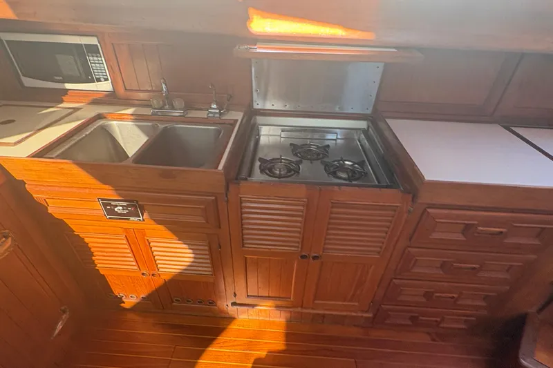 Tenacious Yacht Photos Pics 1987 Mikelson 50 yacht kitchen with stove, sink, and microwave in wooden cabinetry.