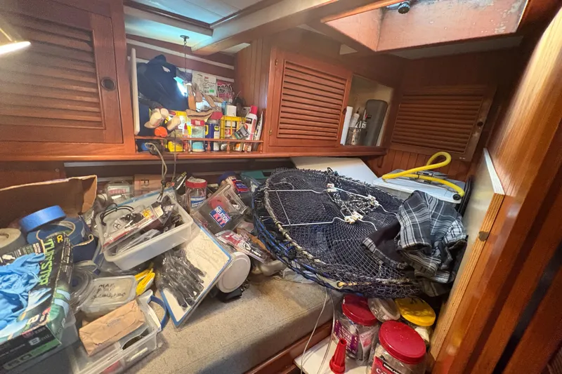 Tenacious Yacht Photos Pics Cluttered cabin interior of 1987 Mikelson 50 boat with various supplies and equipment.