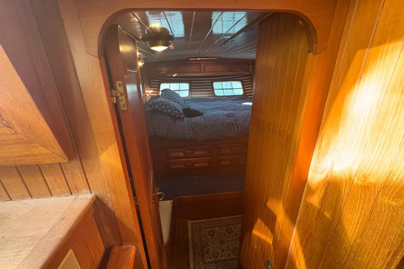 Tenacious Yacht Photos Pics Cozy cabin interior of 1987 Mikelson 50 yacht with wooden finish and bed.