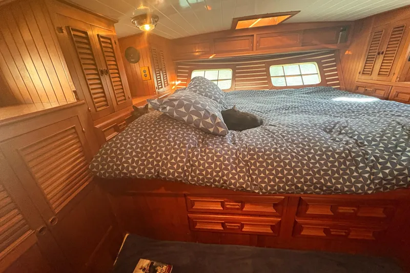Tenacious Yacht Photos Pics Cozy cabin interior of 1987 Mikelson 50 yacht with wooden furnishings and a cat on the bed.