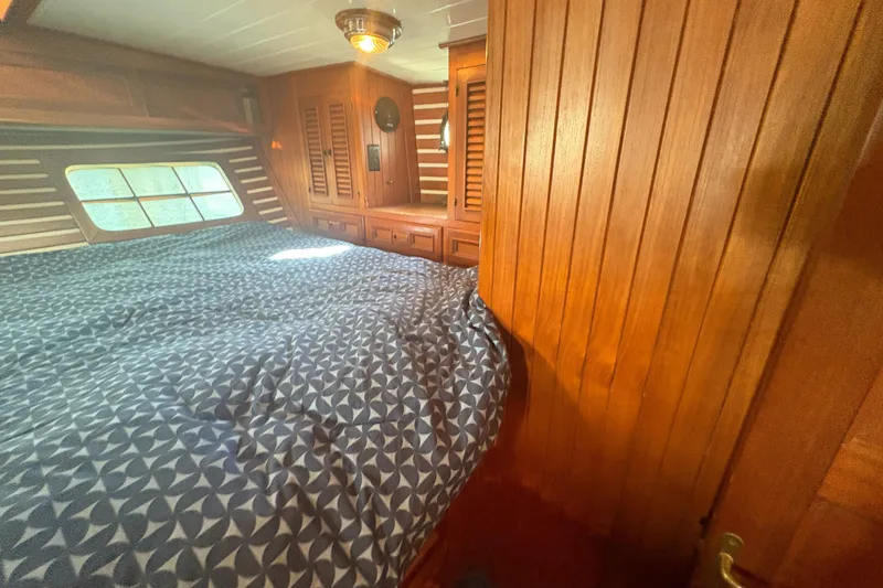 Tenacious Yacht Photos Pics Cozy cabin interior of 1987 Mikelson 50 yacht with wooden paneling and patterned bedding.