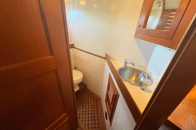 Tenacious Yacht Photos Pics Compact bathroom in a 1987 Mikelson 50 yacht with wooden cabinetry and stainless steel sink.