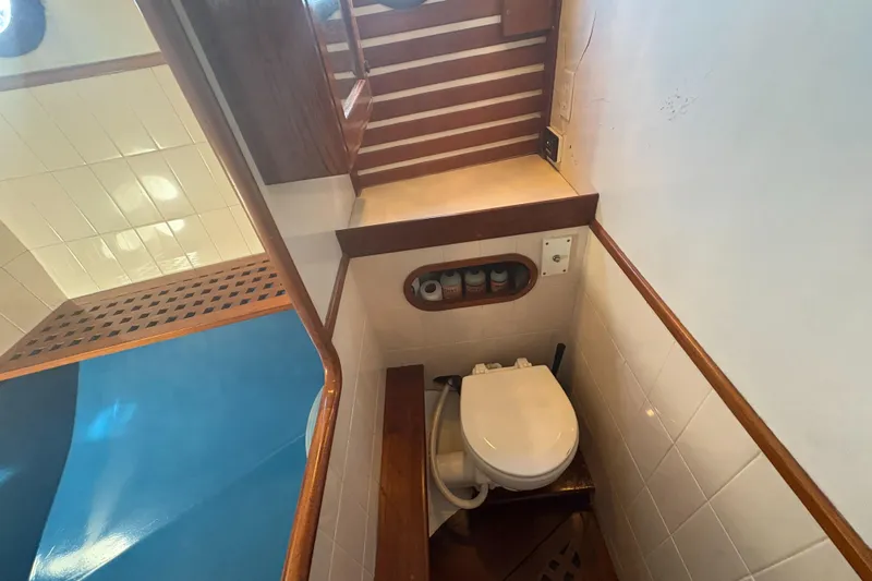 Tenacious Yacht Photos Pics Compact bathroom in 1987 Mikelson 50 yacht with wooden accents and white fixtures.