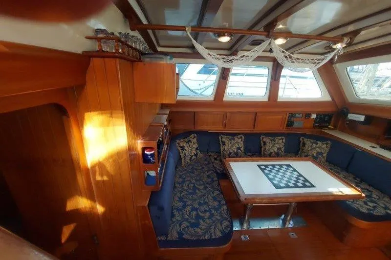 Tenacious Yacht Photos Pics Cozy interior of 1987 Mikelson 50 yacht with blue patterned seating and chessboard table.